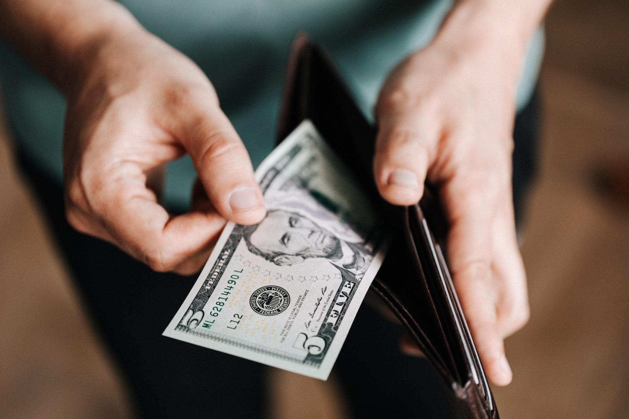 Image of a person taking money from their wallet